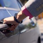 Close-up of a hand opening a car door showcasing elegant attire and style.